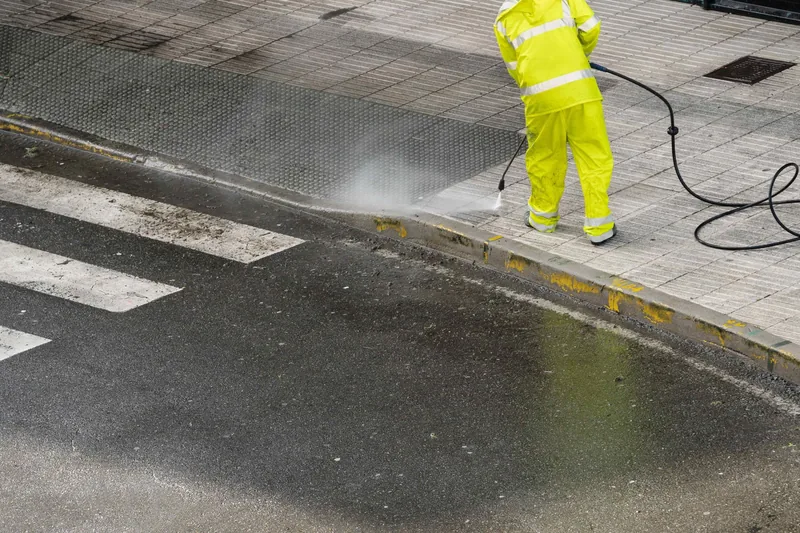 man pressure washing sidewalk