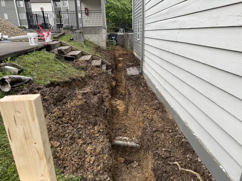 Open drainage trench excavated alongside a condominium building